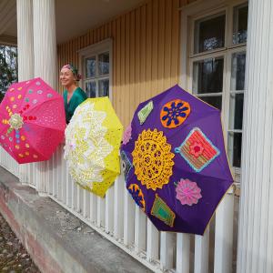 Colorful umbrellas decorated with lace are attached to the exterior railing of the manor house.