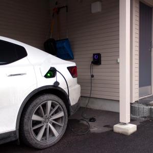 Valkoista sähköautoa ladataan autokatoksessa.