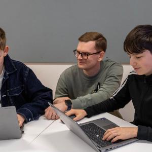 Aleksi Huttu guides two students at the table on how to use Digital Models.