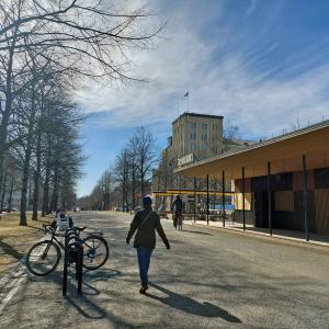 Kävelijä ja pyöräilijä Hämeenpuiston puistokäytävällä.