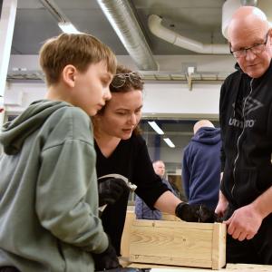 Kaksi aikuista ja yksi lapsi tarkkailevat, mikä vaihe pöntönrakennuksessa alkaa seuraavaksi.