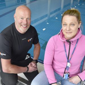 A man and a woman smiling in front of a swimming pool.