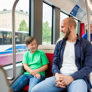 Mies ja poika istuvat bussissa, jonka ikkunasta näkyy tinen bussi.