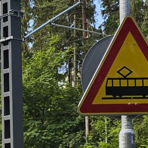 Raitiotieliikennemerkki ja metsää taustalla.,