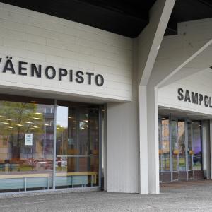 Rakennuksen sisäänkäynti. Kolme isoa ikkunaa. Seinässä teksti "Työväenopisto".