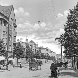 A quiet summer evening at the intersection of Hämeenkatu and Kuninkaankatu in 1913. City residents are getting around on foot, by horse, or by taxi. On the left is the Blom House, and on the right is the Pulla-Helin House. 