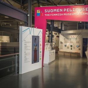 Suomen pelimuseon sisäänkäyntiportti. Taustalla näyttelyn pelejä.