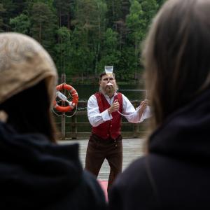 Jonglööri kuvattuna kahden esitystä seuraavan ihmisen päiden takaa.