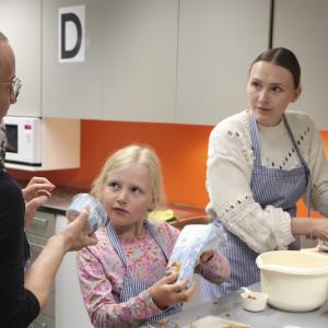 A teacher is helping a mother and daughter prepare a vegetarian meal at the Family Kitchen.