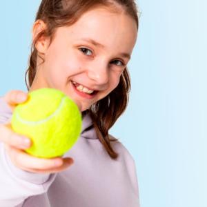 Henkilö pitää tennispalloa kädessään ja hymyilee kameraan.