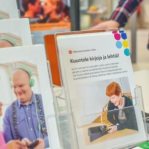 Esitteitä telineessä. Pöydällä kirjanmerkkejä.