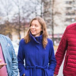 Three people are talking while walking outside.