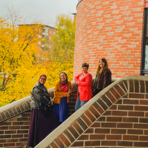 Staff from the association Setlementti Tampere standing cheerfully on the steps of the Hervanta Leisure Centre.