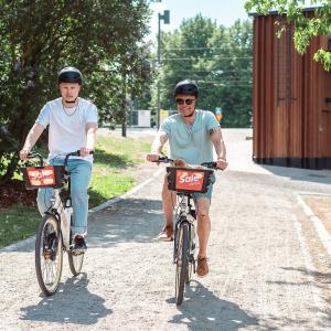 Two cyclists ride Tampere city bikes in Koskipuisto.