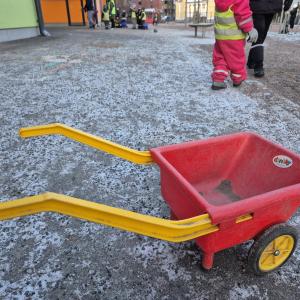 Kuurainen päiväkodin piha ja muoviset kottikärryt.