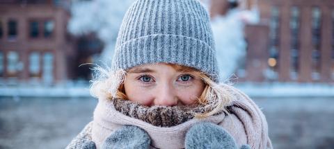 Nuori nainen talvivaatteissa kosken äärellä.
