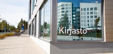 Kirjaston isoon ikkunaan heijastuu kerrostaloja.