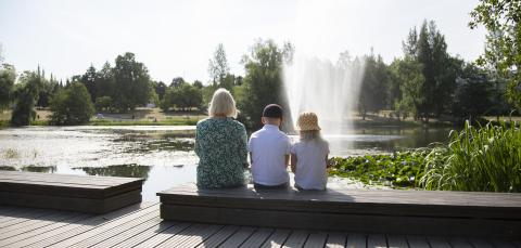 Three people sitting by a pond in Sorsapuisto Park.