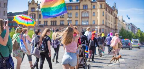 Ihmisiä sateenkaarilippujen kanssa kävelemässä Tampereella.