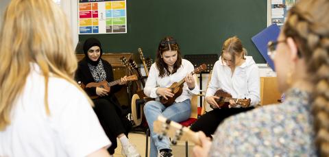 Lukiolaisia soittaa ukuleleja musiikintunnilla.