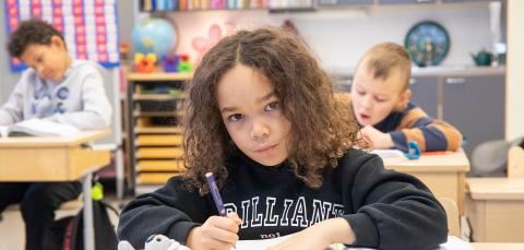 Schoolchildren at their desks doing tasks.