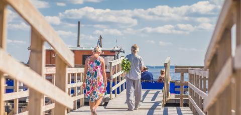 Two people walk on the dock during the summertime.