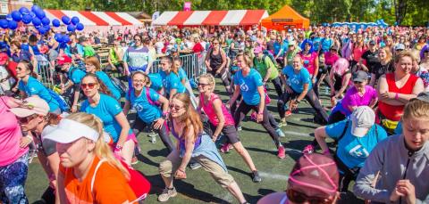 Iso joukko naisia venyttelee samaan tahtiin ennen juoksukisan alkua. 