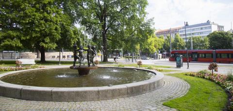 A fountain in Pyynikki Church Park, with a tram in the background.