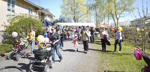 Perheitä kulkemassa ulkona kaupunginosatapahtumassa.