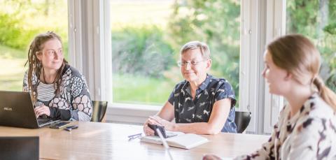 Kolme naista työpöydän äärellä suunnittelemassa.