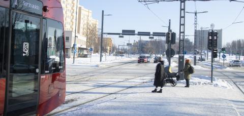 Liikennettä talvisessa Kalevassa: raitiotievaunu, jalakulkijoita, autoja ja kauempan bussi tulossa.