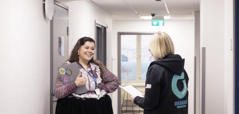 Romanipukuinen kaupungin työntekijä keskustelee toisen kaupungin työntekijän kanssa.