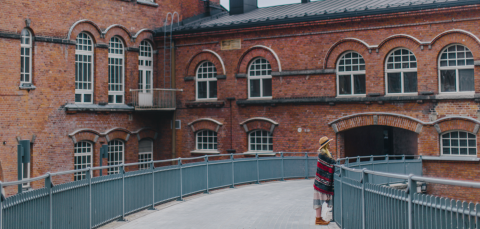 On the footbridge through the red-brick Frenckell building, a person leaning on the railing.
