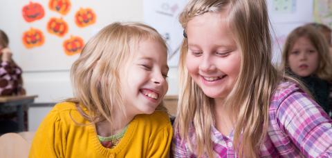 Kaksi iloista lasta koulussa oppitunnilla.