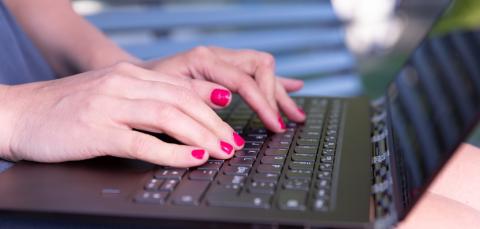 Henkilön kädet kirjoittamassa tietokoneella.