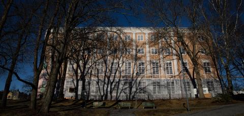 The large four-story building is covered with a visible tarpaulin due to facade renovation.