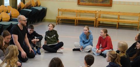 Opettaja ja oppilaat istuvat ringissä.
