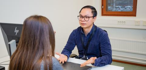 A person giving guidance to another person sitting by a table
