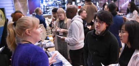 Kaupungin työntekijä keskustelee kahden asukkaan kanssa. Taustalla näkyy paljon muistakin asukkaita.