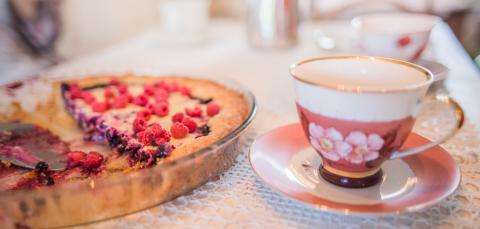 Kahvikuppi ja marjapiirakka pöydällä.