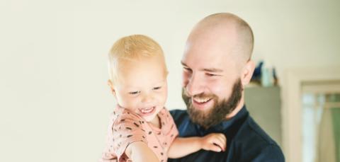 Hymyilevä lapsi isän sylissä.