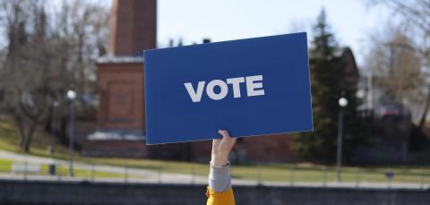 The person is holding a sign saying &quot;vote&quot;.