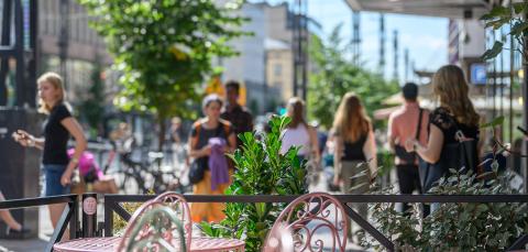 Ihmisiä kävelemässä kesäisellä Hämeenkadulla aurinkoisena päivänä. Etualalla näkyy terassin pöytiä ja tuoleja.