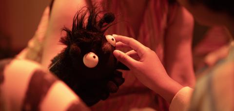 Lapsen käsi silittämässä kimalaiskäsinukkea.