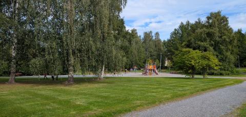 Perkiönpuiston puistokäytävä, taustalla leikkipaikka.