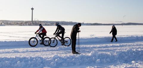 Kävelijöitä ja pyöräilijöitä talvimaisemassa.