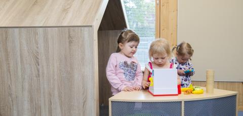 Kolme lasta leikkii kassakoneella.