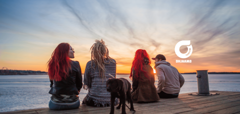 Neljä nuorta istumassa laiturilla ja katsomassa auringonlaskua