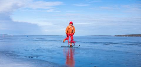 A young person is kick sledding on the frozen lake.