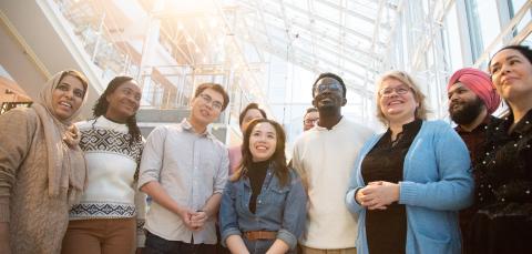 A large group of smiling Tampere residents from different cultures standing side by side.